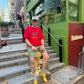 Person in red shirt and yellow shoes standing on a staircase with a green building in the background